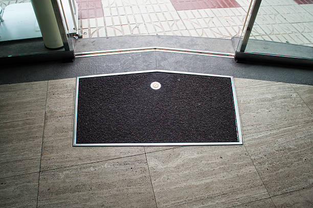 Mat on the gray stone floor near glass sliding door Black with metal frame mat on the gray stone floor near metal glass sliding door entrance sign stock pictures, royalty-free photos & images
