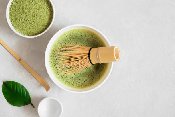 Matcha green tea. Making matcha tea with a bamboo whisk on a gray background. Japanese tea ceremony. View from above. Space for text. stock photo