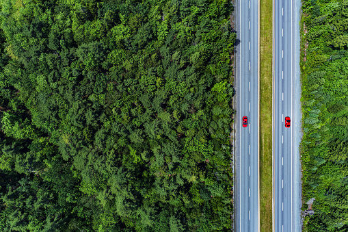 Two red cars pass each other a multilane highway.