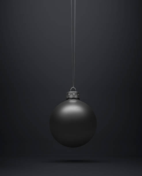 Matte black Christmas ball hanging centered on a black background. Matte black Christmas ball hanging centered on a black background for seasonal Holiday celebrations and themes matte finish stock pictures, royalty-free photos & images