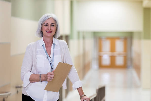 Mature adult school counselor takes break in corridor As she goes from her office to the cafeteria, a mature adult counselor takes a break for photo. administrator stock pictures, royalty-free photos & images