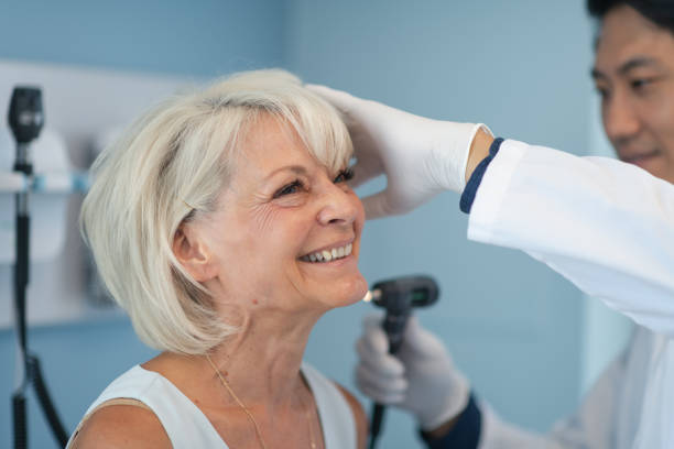 mujer adulta madura en consulta médica con el médico masculino - hearing aids fotografías e imágenes de stock