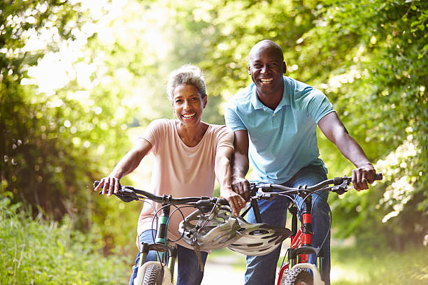 Mature African American Couple On Cycle Ride In Countryside Mature African American Couple On Cycle Ride In Countryside Smiling At Camera mature couple stock pictures, royalty-free photos & images