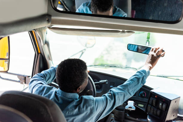 mature african american driver adjusting back view mirror at bus  school bus driver stock pictures, royalty-free photos & images
