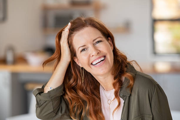 Mature beautiful woman laughing Portrait of cheerful beautiful woman touching hair after anti hair loss treatment. Successful mature woman at home smiling looking at camera. Middle aged redhead woman in casual laughing. human hair stock pictures, royalty-free photos & images