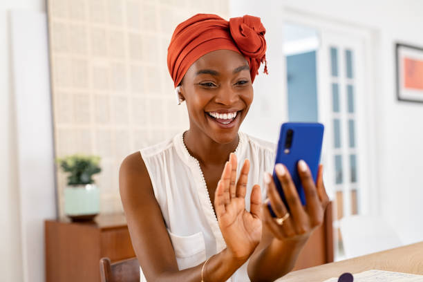Mature black woman doing video call on smartphone at home stock photo