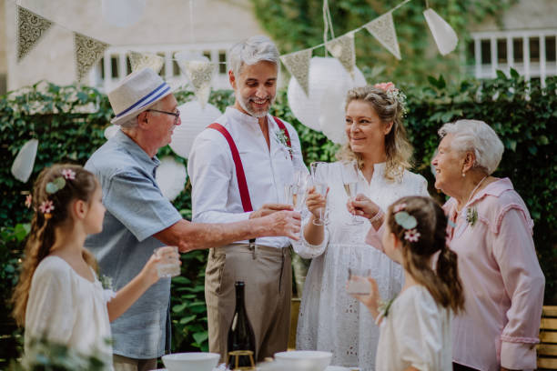 Mature bride and groom toasting with family at wedding reception outside in the backyard. stock photo
