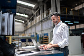 istock Mature businessman using laptop in a factory 1363139896