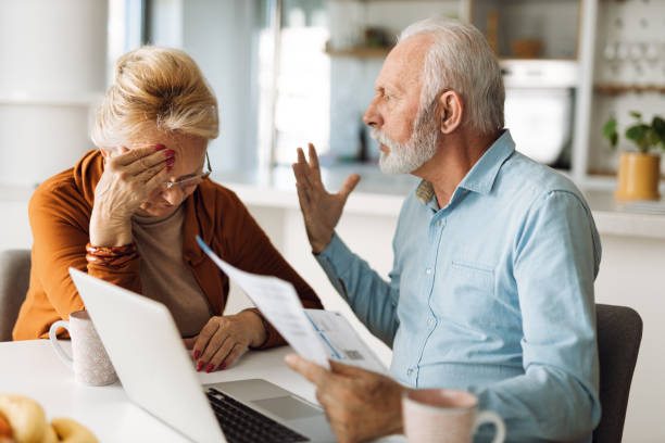 Mature couple arguing while having problems with paying their bills over Internet stock photo