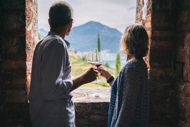 het rijpe paar geniet van wat rode wijn in oud italiaans kasteel - castle couple stockfoto's en -beelden