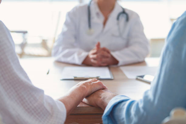 Mature couple holding hands at a doctors office stock photo