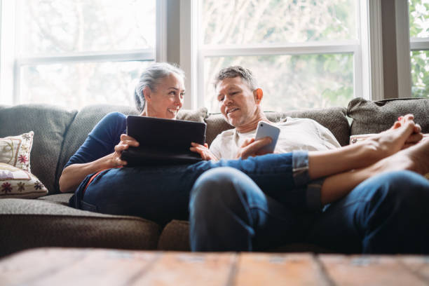 pasangan dewasa bersantai dengan tablet dan smartphone - membaca memandang potret stok, foto, & gambar bebas royalti