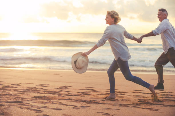 ouder paar uitgevoerd en spelen op het strand bij zonsondergang of zonsopgang. - hardlopen vorouw stockfoto's en -beelden