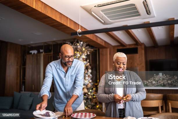 Mature couple setting the table for Christmas lunch or dinner at home