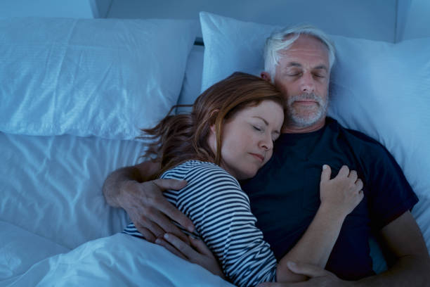 Mature couple sleeping at night Senior man and woman sleeping and dreaming together in a deep sleep. Mature woman embracing and sleeps on her husband's chest while sleeping at night. Loving couple resting in their bed, copy space. man sleeping in bed top view stock pictures, royalty-free photos & images