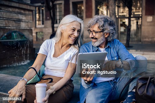 istock Mature couple taking a break while sightseeing and using tablet 1355468343