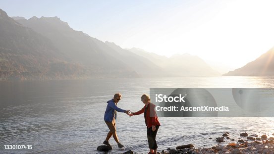 istock Mature couple walk across rocks on Lake Lugano 1330107415