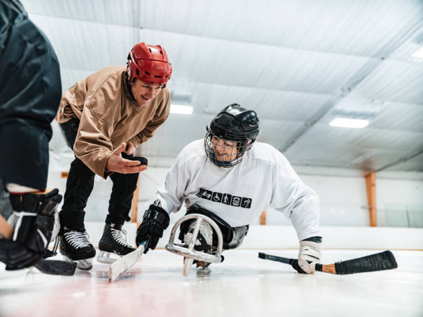 Mature Disabled Latin woman, her partner and trainer practising sledge hockey stock photo