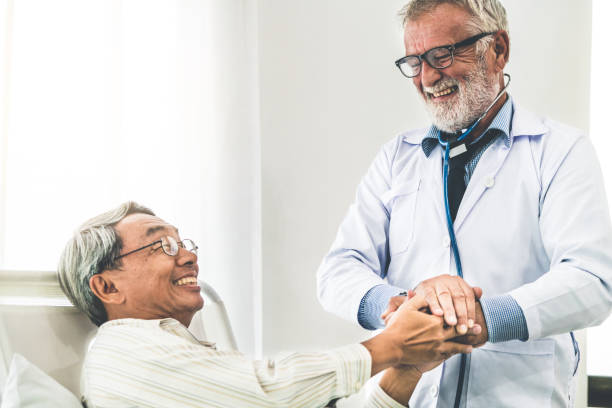 Mature doctor and senior patient in hospital ward. Mature doctor talking and examining health of senior patient in hospital ward. Medical healthcare and doctor staff service concept. inpatient stock pictures, royalty-free photos & images