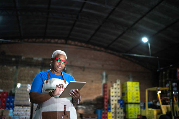 Mature employee using digital tablet at warehouse Mature employee using digital tablet at warehouse market retail space photos stock pictures, royalty-free photos & images