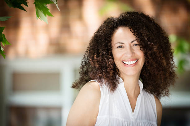 Mature Ethnic Woman Smiling At The Camera. She is outside in front of her house stock photo