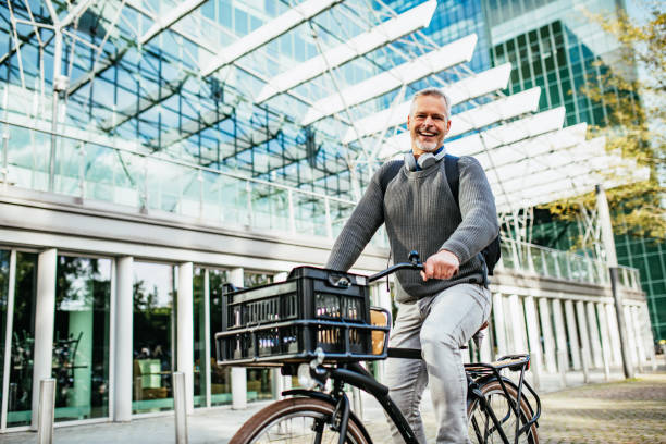 Mature gray hair man riding bicycle and contributes to eco-friendly environment Portrait of mature or senior man in the modern city, commuting to work dutch culture stock pictures, royalty-free photos & images