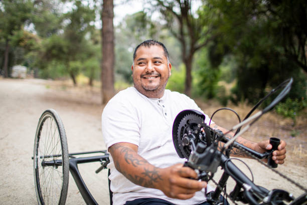 Mature Hispanic Man Riding Handcycle A mature hispanic man rides his handcycle. He is a double amputee. adult tricycle stock pictures, royalty-free photos & images