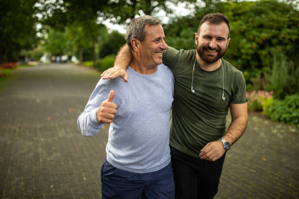 mature man and his son jogging in park on autumn morning - adulto de idade mediana imagens e fotografias de stock