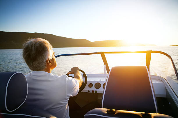 mature man driving speedboat stock photo