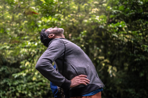 homem maduro experimentando dor nas costas ou alongamento em uma floresta - lombar - fotografias e filmes do acervo