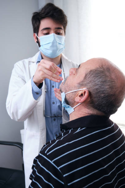 Mature man getting PCR test at doctor's office during coronavirus pandemic. Doctor wearing gloves and mask doing the nasal coronavirus test. stock photo