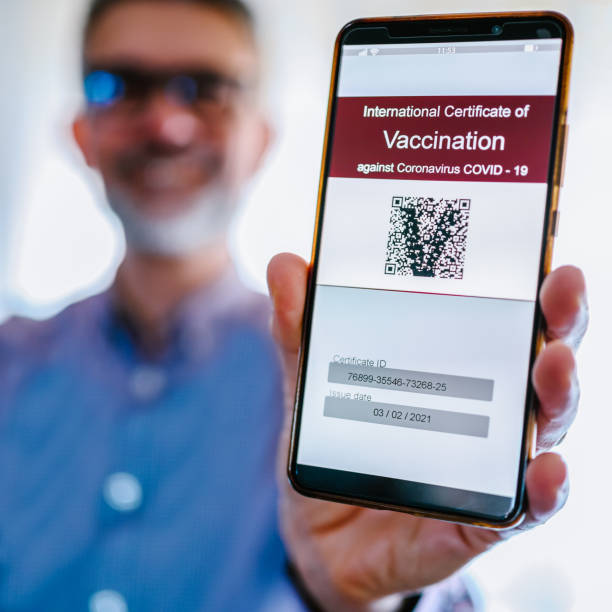 homme mûr retenant le certificat de vaccination covid-19 - pass sanitaire photos et images de collection