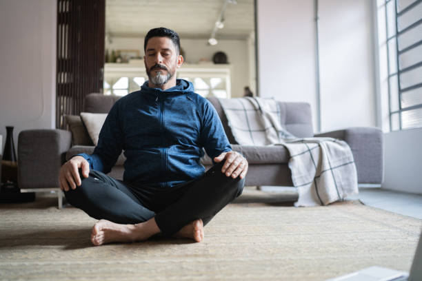 Mature man meditating at home stock photo