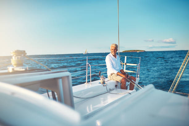 Mature man sitting on his boat out at sea stock photo