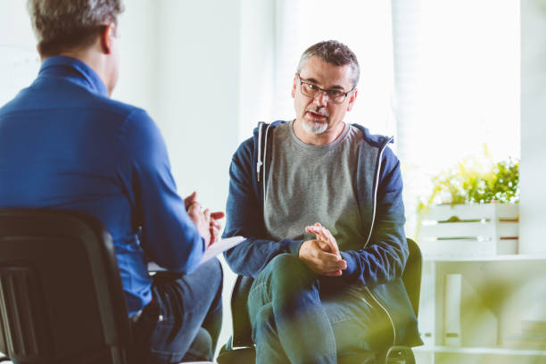 Mature man talking with psychotherapist in his office Mature psychotherapist talking with depressed man. Coach is discussing about mental illness with man. They are in meeting in psychotherapeutic office mental health professional photos stock pictures, royalty-free photos & images