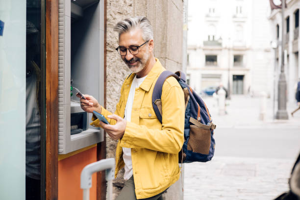 Mature tourist taking the money on the ATM stock photo