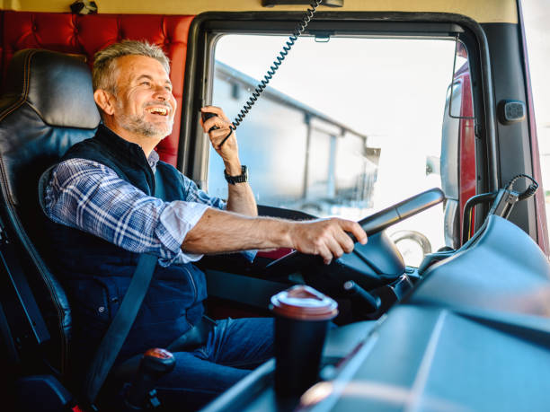 Mature truck driver CB talking CB Radio Talk While on the Road. Truck Driver Using Radio To Contact Other Convoy Drivers. truck driver stock pictures, royalty-free photos & images