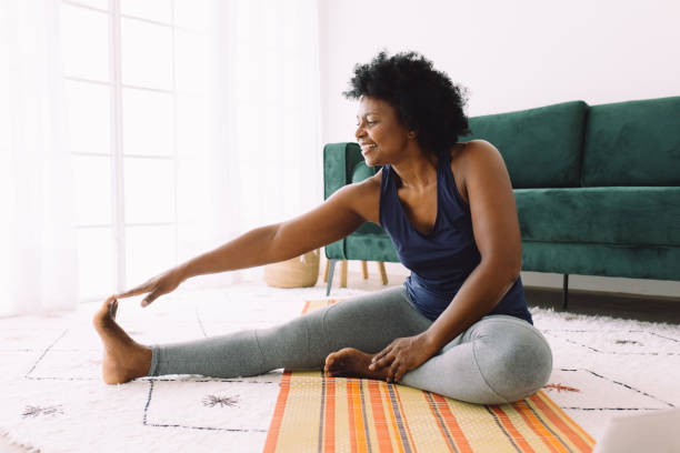 Mature woman doing stretching workout at home stock photo