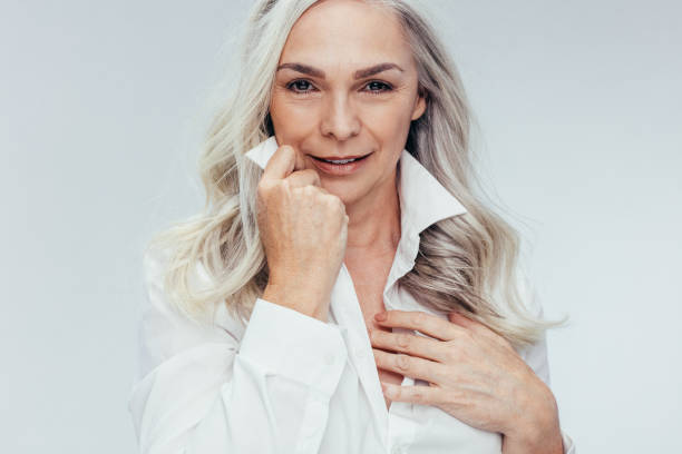 Mature woman looking attractive Attractive mature woman posing against white background. Senior woman looking attractive in white shirt. mid adult women stock pictures, royalty-free photos & images