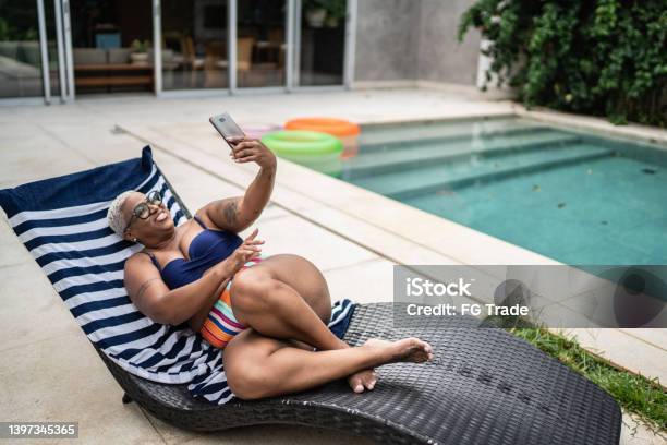 Mature woman on a video call on the mobile phone in a pool at home