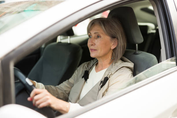 Mature woman sitting behind wheel in car stock photo