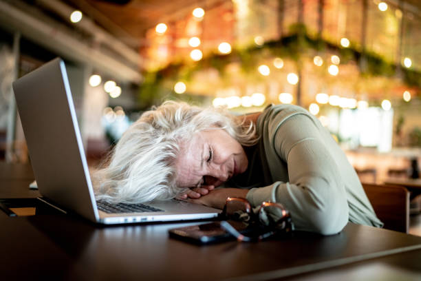 mature woman taking a nap at the office - nap middle age woman bildbanksfoton och bilder