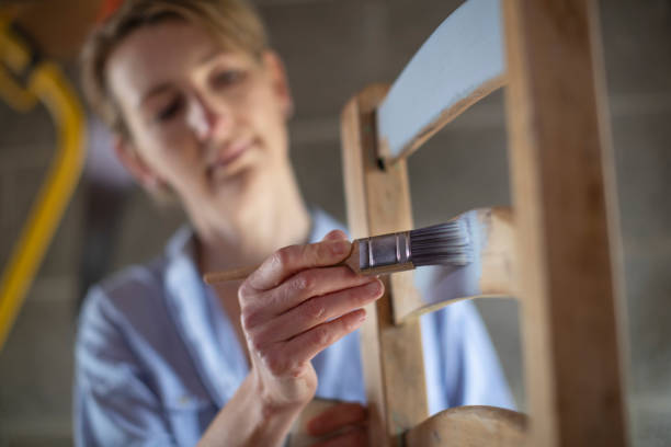donna matura upcycling mobili in officina a casa pittura sedia di legno - upcycling foto e immagini stock