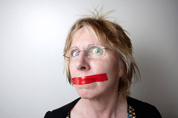 Mature woman with red tape over mouth Mature woman with red tape over mouth human mouth gag adhesive tape women stock pictures, royalty-free photos & images