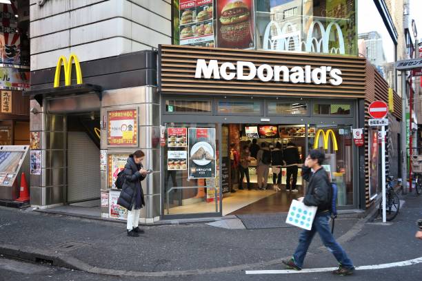 McDonald's Japan Tokyo: People walk by McDonald's fast food restaurant in Shibuya, Tokyo. McDonald's had 36,900 restaurants worldwide in 2016. mcdonalds japan stock pictures, royalty-free photos & images