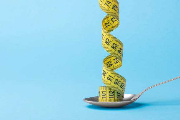 Measuring tape on a tablespoon, minimum creative concept-diet healthy lifestyle. stock photo