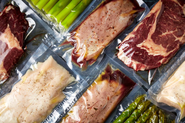Meat and asparagus vacuum sealed on black table, from above Duck breast, chicken breast, beef steak and asparagus vacuum sealed ready for sous vide cooking, on black background, top view airtight stock pictures, royalty-free photos & images