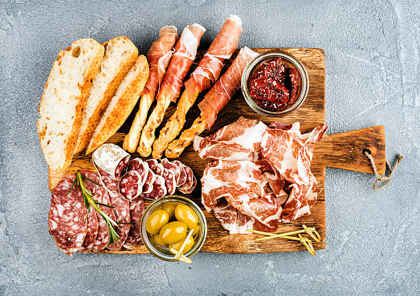 Meat appetizer selection or wine snack set. Variety of smoked Meat appetizer selection or wine snack set. Variety of smoked meat, salami, prosciutto, bread sticks, baguette, olives and sun-dried tomatoes on rustic wooden board, top view, horizontal delicatessen stock pictures, royalty-free photos & images