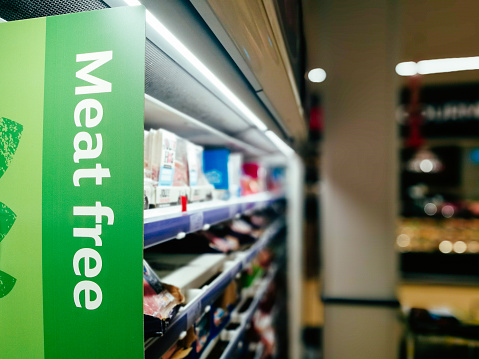 Sign in a supermarket aisle with the words 'meet free'. Focus on the sign with the supermarket shelves defocused beyond.