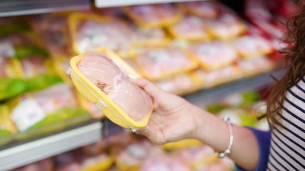 vlees in voedsel winkel. vrouw kiezen verpakt verse kippenvlees in de supermarkt - kip vlees stockfoto's en -beelden